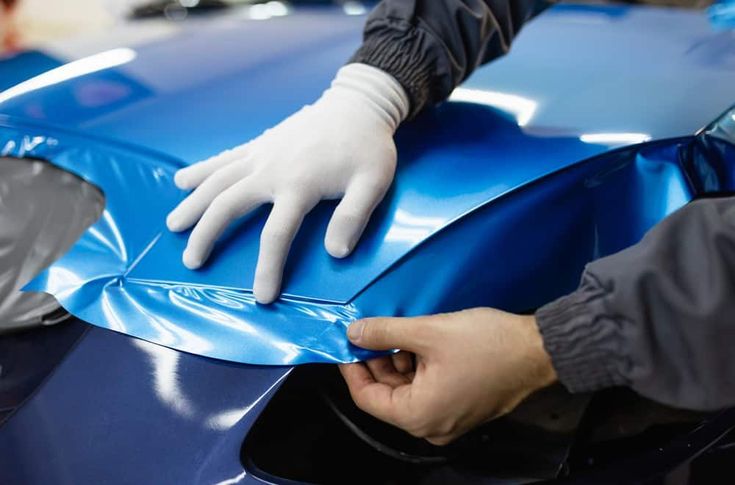 Person applying blue car wrap to a vehicle