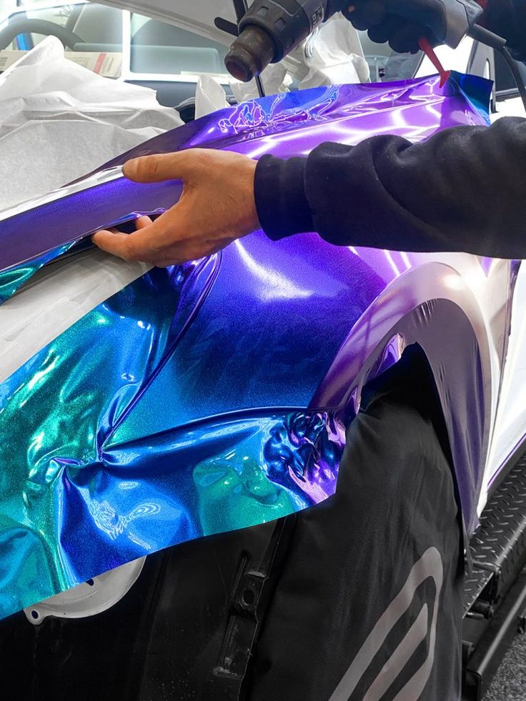 Person applying a colorful vinyl wrap to a vehicle