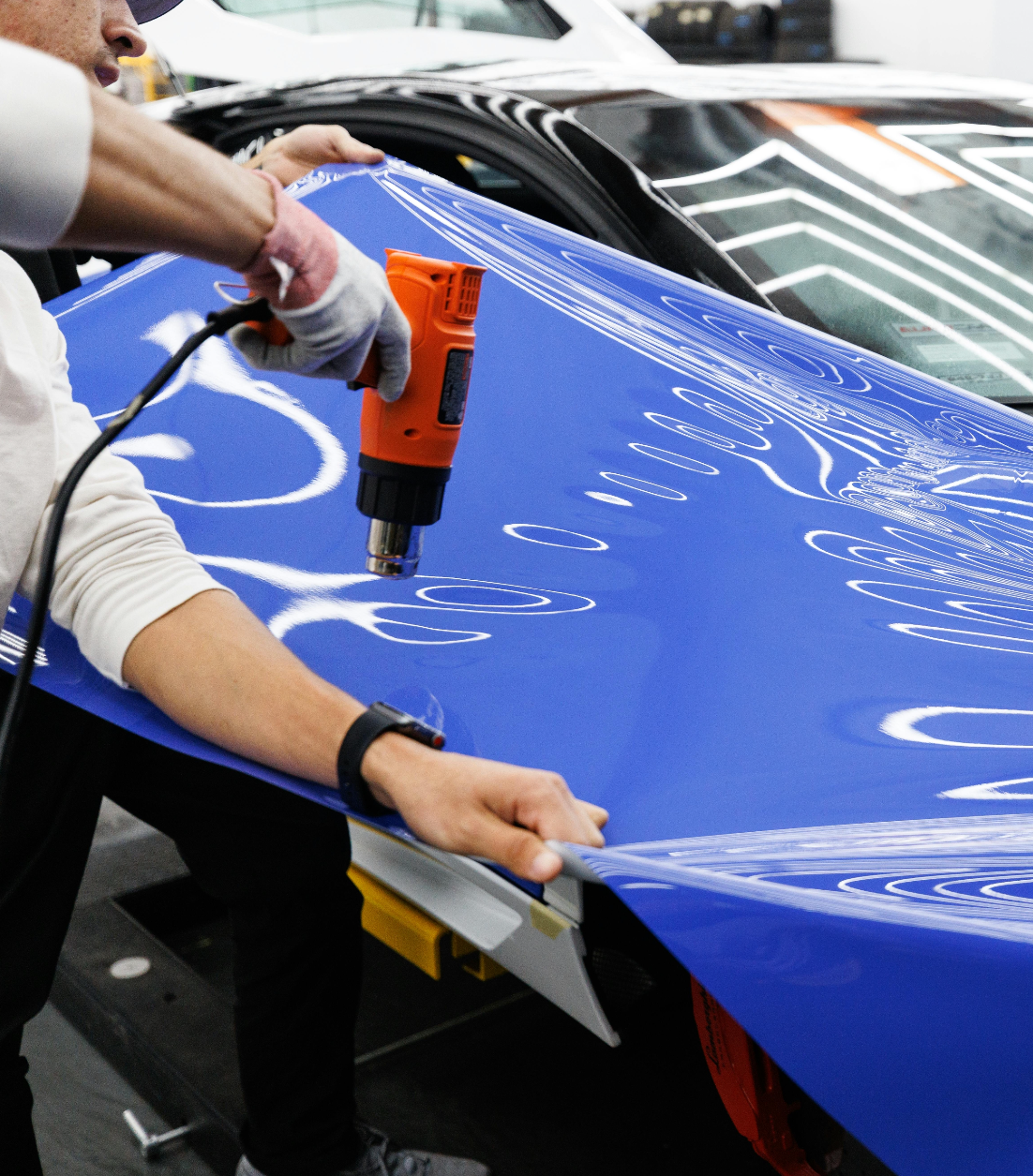 Vehicle wrap installer using a heat gun on vinyl wrap