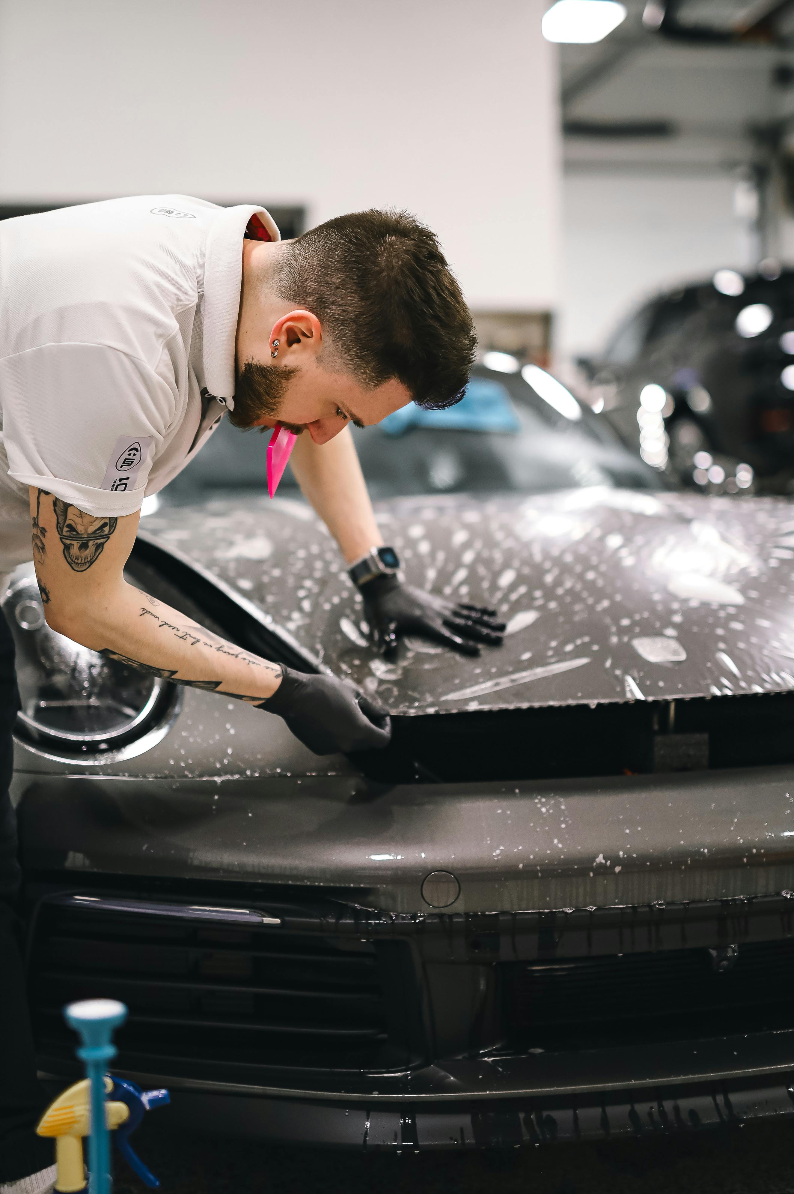 PPF installer applying clear protection film to a vehicle hood.